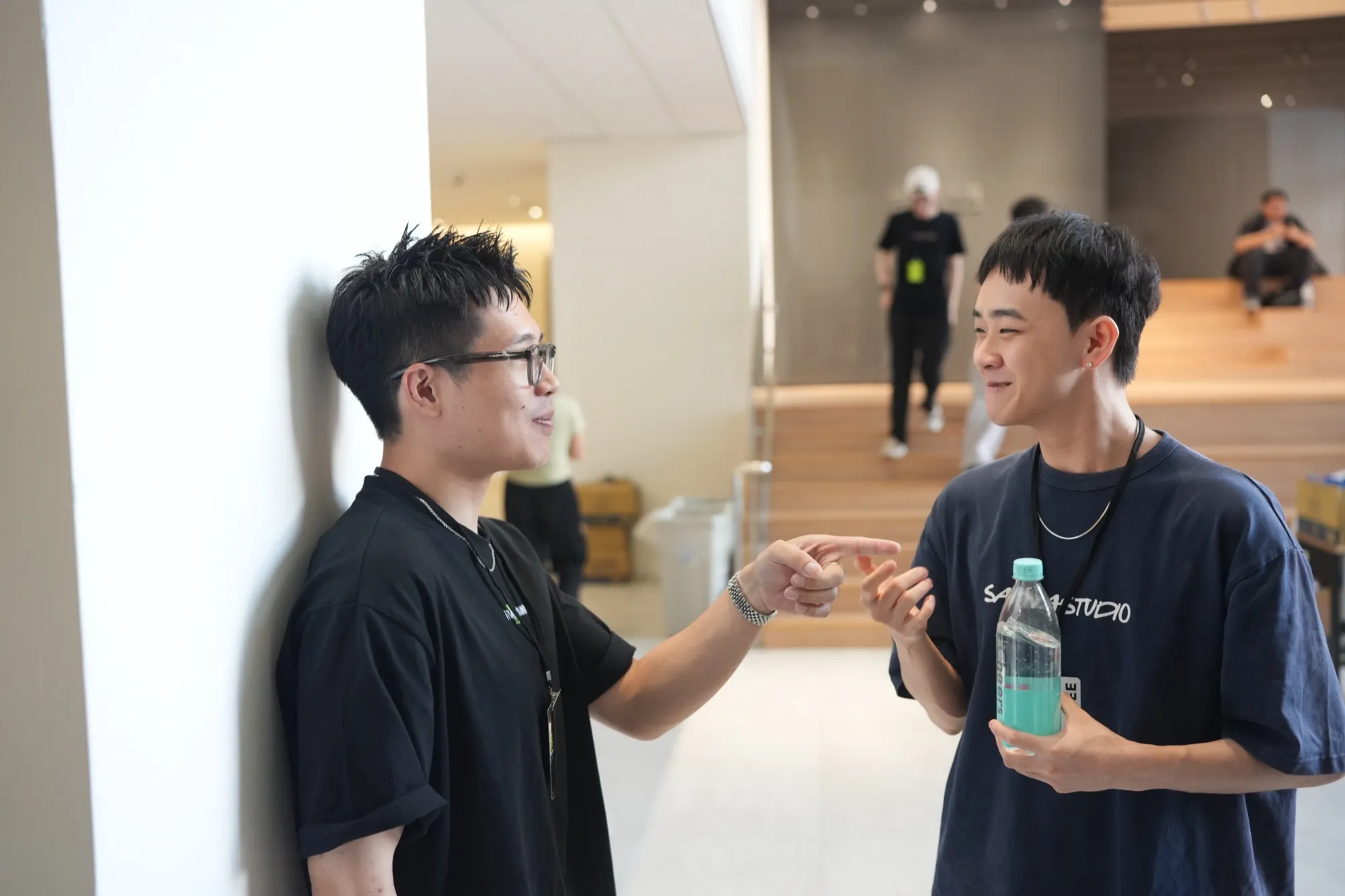 iPlayground 2026 Day 2 兩位參與者在明亮的大廳裡微笑聊天，其中一人穿著黑色上衣